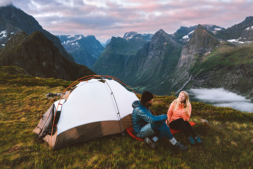 Couple man and woman traveling together with camping tent gear romantic vacations friends hiking adventure outdoor family healthy lifestyle climbing mountains of Norway Valentines day holiday