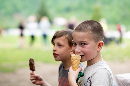 an African american child eats ice cream on a hot day. Ice cream in a waffle cone. A happy and contented child in a pink dress at summer.