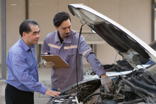 istock Two guys are standing by a car with the hood open, staring at the engine inside. 2007558144