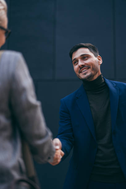 Portrait of a Handsome Businessman Introducing Himself to an Anonymous Woman Close up shot of a handsome smiling man shaking hands with an anonymous woman outside the office building. woman necktie stock pictures, royalty-free photos & images