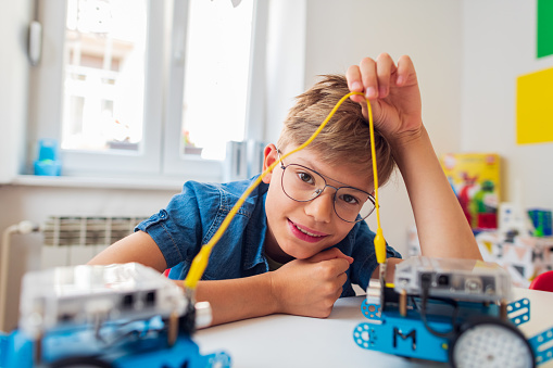 Elementary school student boy in a robotics and technology class -holds a robot model