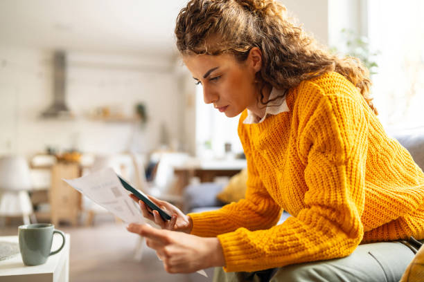 istock While organizing home finances, woman using mobile phone to calculate 2007594498