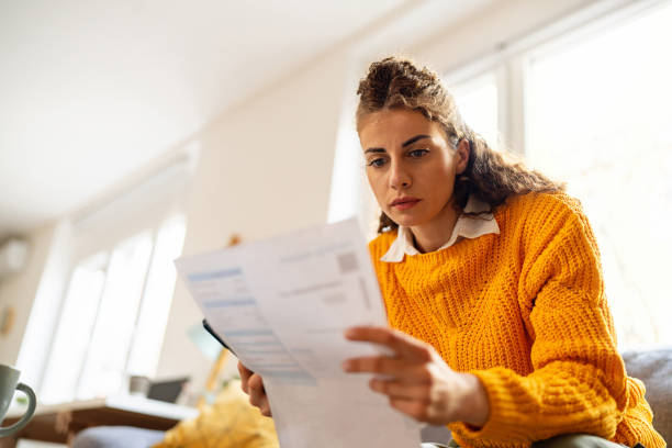 istock While organizing home finances, woman using mobile phone to calculate 2007594499