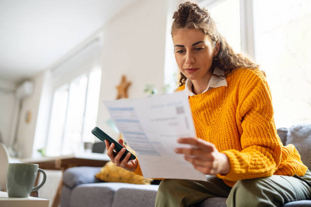 istock While organizing home finances, woman using mobile phone to calculate 2007594508