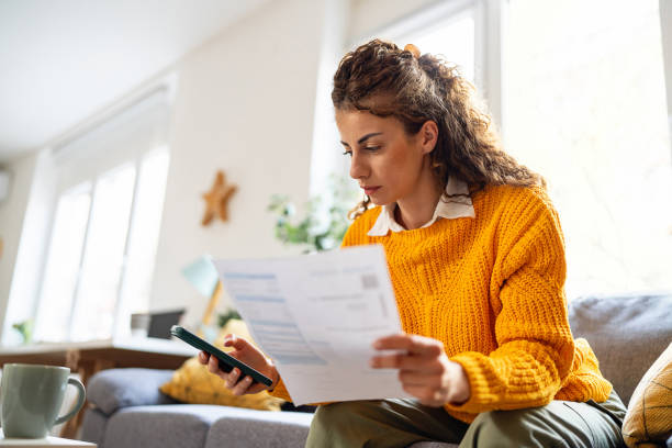 istock While organizing home finances, woman using mobile phone to calculate 2007594509