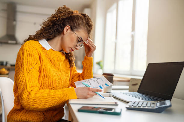 Worried young Caucasian woman organizing home finances A worried young Caucasian woman, organizing home finances, during inflation time managing stress stock pictures, royalty-free photos & images
