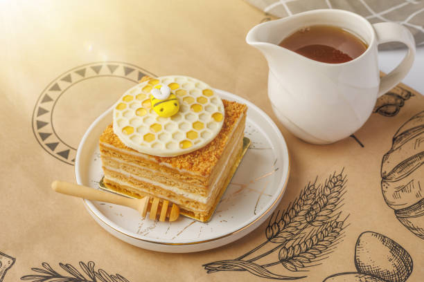 Napoleon cake with cup of honey on tablecloth, closeup