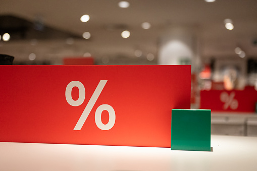 Red-coloured sales sign displaying percentage discounts.