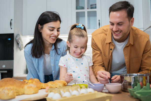 istock Excited girl with parents, coloring Easter eggs in the kitchen 2007601891
