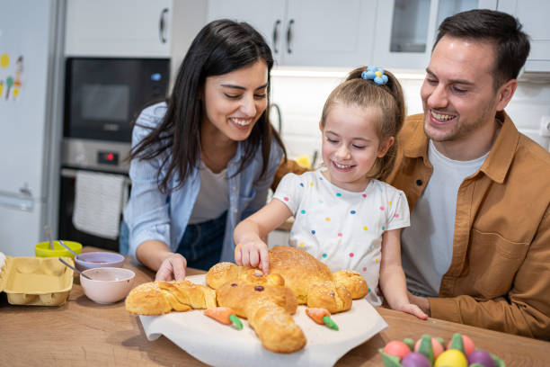 istock Toddler girl touching baked bread in a shape of an Easter Bunny, during Easter celebration with her parents 2007604055