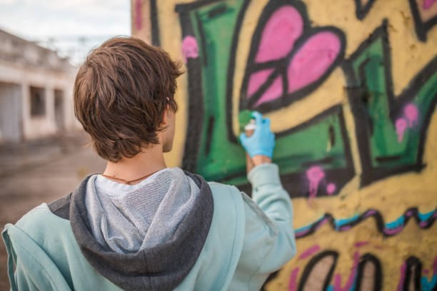 廃墟となった建物の壁に落書きを描く男性ストリートアーティストの後ろ姿、接写 - graffiti men wall street art ストックフォトと画像