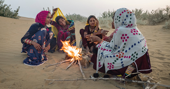 Indian kids resting on sand dune, next to a bonfire, Thar Desert, Rajasthan, India