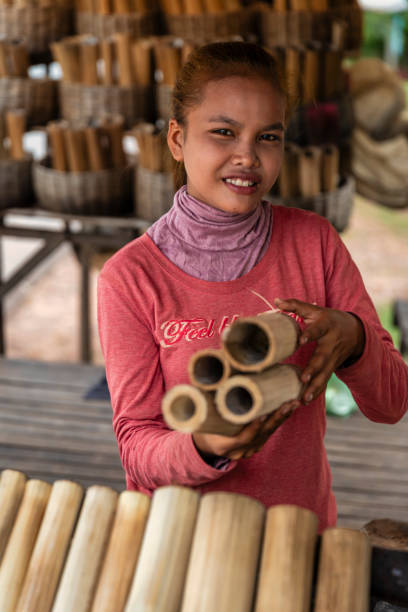 Cambodian woman selling kralan - sticky rice in bamboo, Cambodia Cambodian woman selling sticky rice in bamboo on a street market, Cambodia. Kralan is made by roasting a mixture of glutinous rice, black-eyed peas, coconut milk, grated coconut in bamboo tubes over a fire. cambodia food stock pictures, royalty-free photos & images