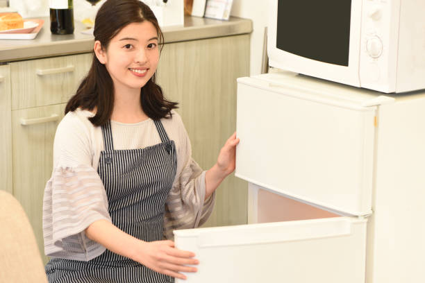 istock Beautiful young Asian woman smiling using refrigerator indoors 2007633336