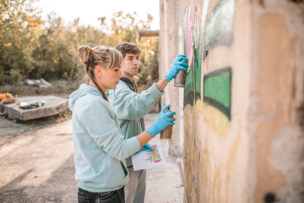 Side view of two young street artists drawing graffiti