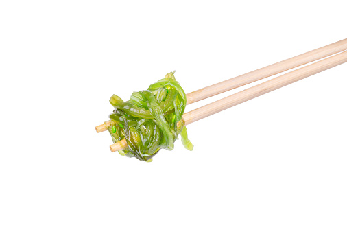 Healthy seaweed chuka salad on Chinese chopsticks on a white background