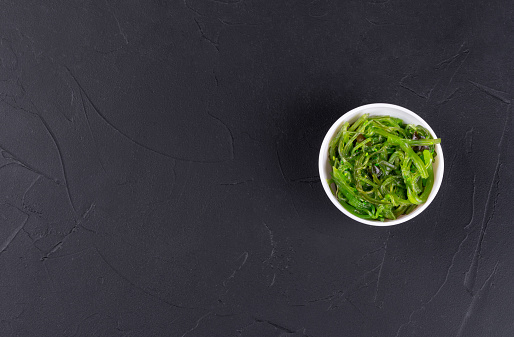 Chuka seaweed salad in a white plate on a dark background. Copy space, top view