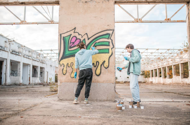 istock Two friends draw graffiti on the wall of an abandoned building 2007653051