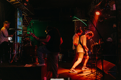 Happy young people have fun and dance in a nightclub during a concert - focus on hands with dj in the background - black orange filter