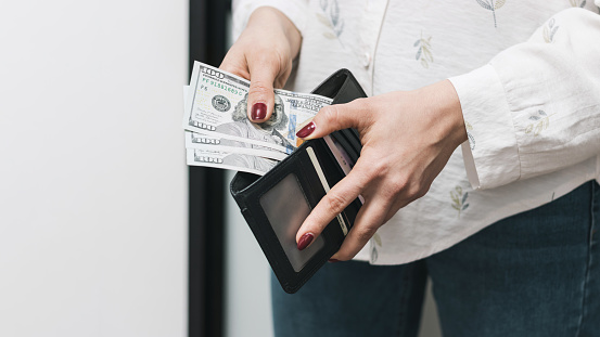 Woman's hands taking out money from wallet, dollar banknote cash.