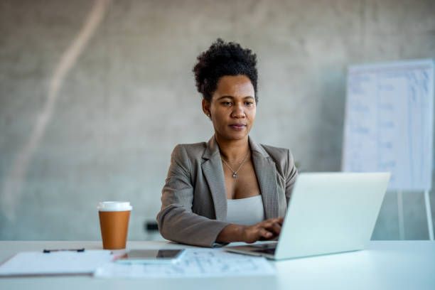 Black woman in office for research, email and networking.