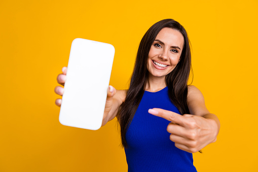 Photo of pretty adorable lady dressed blue top showing finger modern gadget empty space isolated yellow color background.