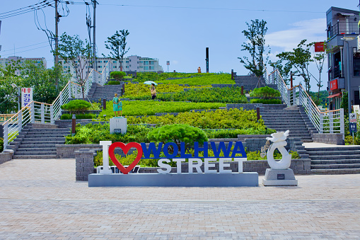 Gangneung City, South Korea - July 29th, 2019: At the end of Wolhwa Street, a staircase flanked by lush green landscaping and featuring a sign that proclaims I [heart] Wolhwa Street leads visitors towards Namdae Stream, inviting exploration and admiration of the natural and urban harmony.
