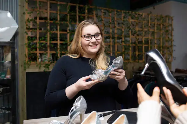 Photo of Two young woman choosing shoes in a second hand shop