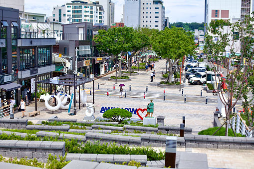 Gangneung City, South Korea - July 29th, 2019: From the top of the staircase at the end of Wolhwa Street, a view looking down onto Wolhwa Street and Gangneung Jungang Market, showcasing the vibrant urban life and green spaces of the area.