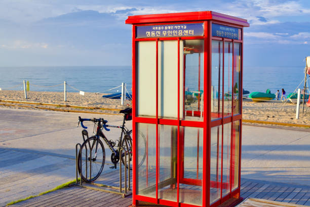 Gangneung City, South Korea - July 29th, 2019: View from the bicycle certification center showcases a parked bicycle, with the charming landscape of Jeongdongjin in the background, featuring sandy beaches, a few boats, and the calm waters of the East Sea.