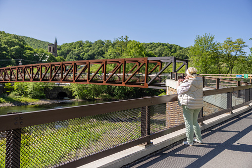 Lehigh River bridge: woman photographs landmarks from a bridge, providing an overview of Jim Thorpe, Pennsylvania