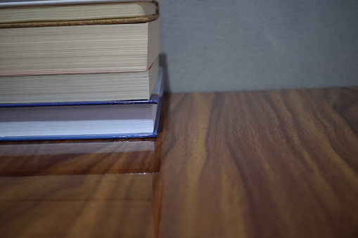 non edited photo of Front view Pile of books on a wooden table against a grey background.