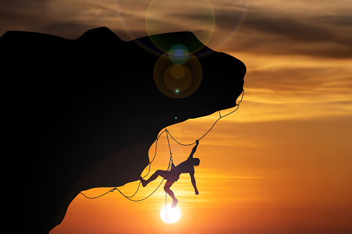 A climber's silhouette against a golden sunset sky, capturing the essence of adventure and the climber's pursuit.