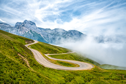 Mountain top road with hairpin bends and cloud and cyclist