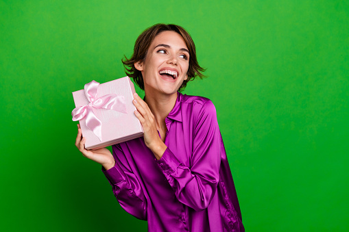 Portrait photo of smiling young happy businesswoman just received gift box looking novelty xmas day isolated on green color background.