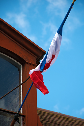 French flag, twisted around flagpole against blue sky
