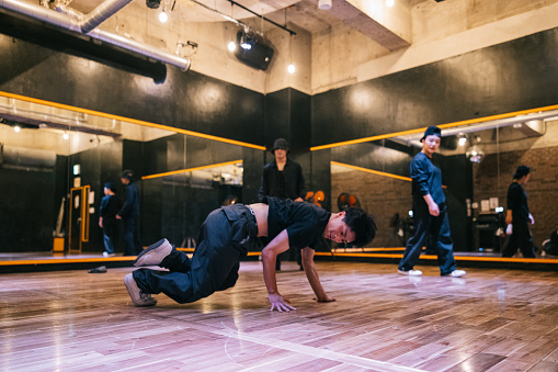 Young Japanese man performing his breakdance moves to friends in a Hip Hop dance studio.