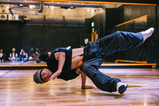 Young Japanese man showing his dance skill to the camera, performing hip hop moves in a dance studio.