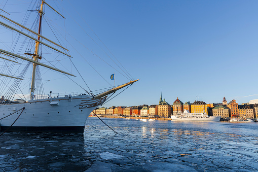 Beautiful urban scene at morning with Stockholm buildings lit at sunrise from warm light and the frozen harbour in the foreground, Stockholm, Sweden, Scandinavia, Europe