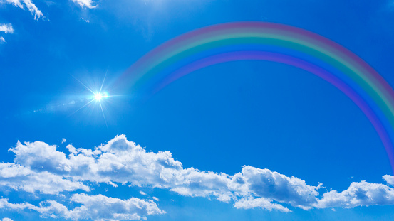 Bright blue sky with rainbow and sunshine