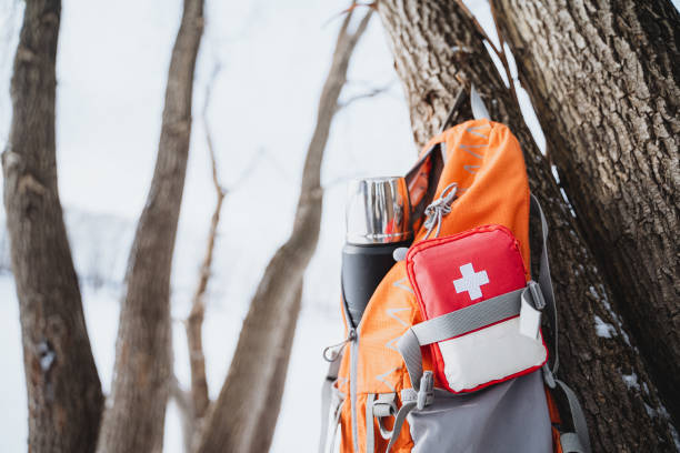 istock Orange backpack with a first aid kit and a thermos bottle hanging on a tree in the winter forest. 2007866336