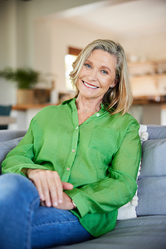 Portrait of a mature woman smiling while sitting on a comfortable sofa in a her living room