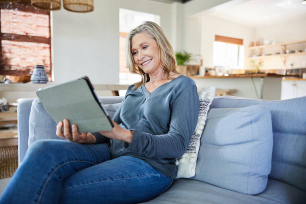 istock Smiling mature woman using a digital tablet on her sofa 2007881275
