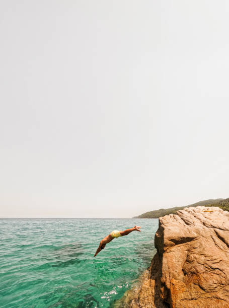 istock Young man jumps off and dives into the sea 2007883434