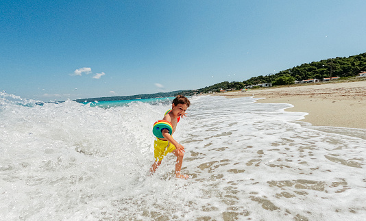 Photo of a young boy who is having fun playing on the beach with the sea waves