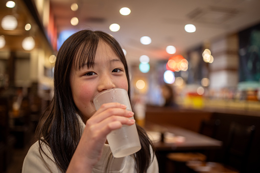 Teenage girl drinking a glass of water in cafe