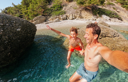 Photo of a father and son jumping into the sea from the rocks