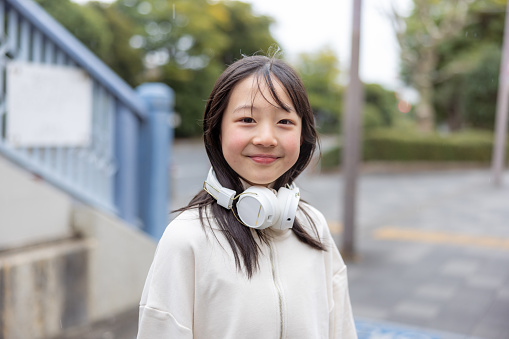 Portrait of teenage girl putting headphones around her neck on street