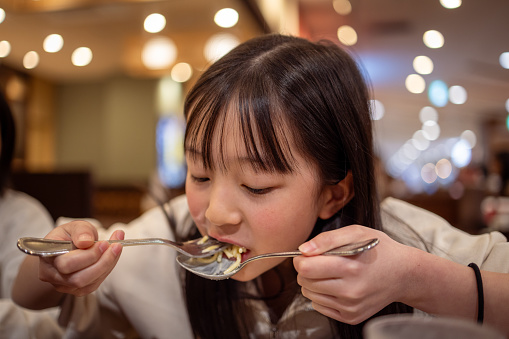 Teenage girl eating pasta for lunch in restaurant