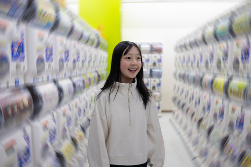 Teenage girl walking in amusement arcade for choosing capsule toy vending machine
